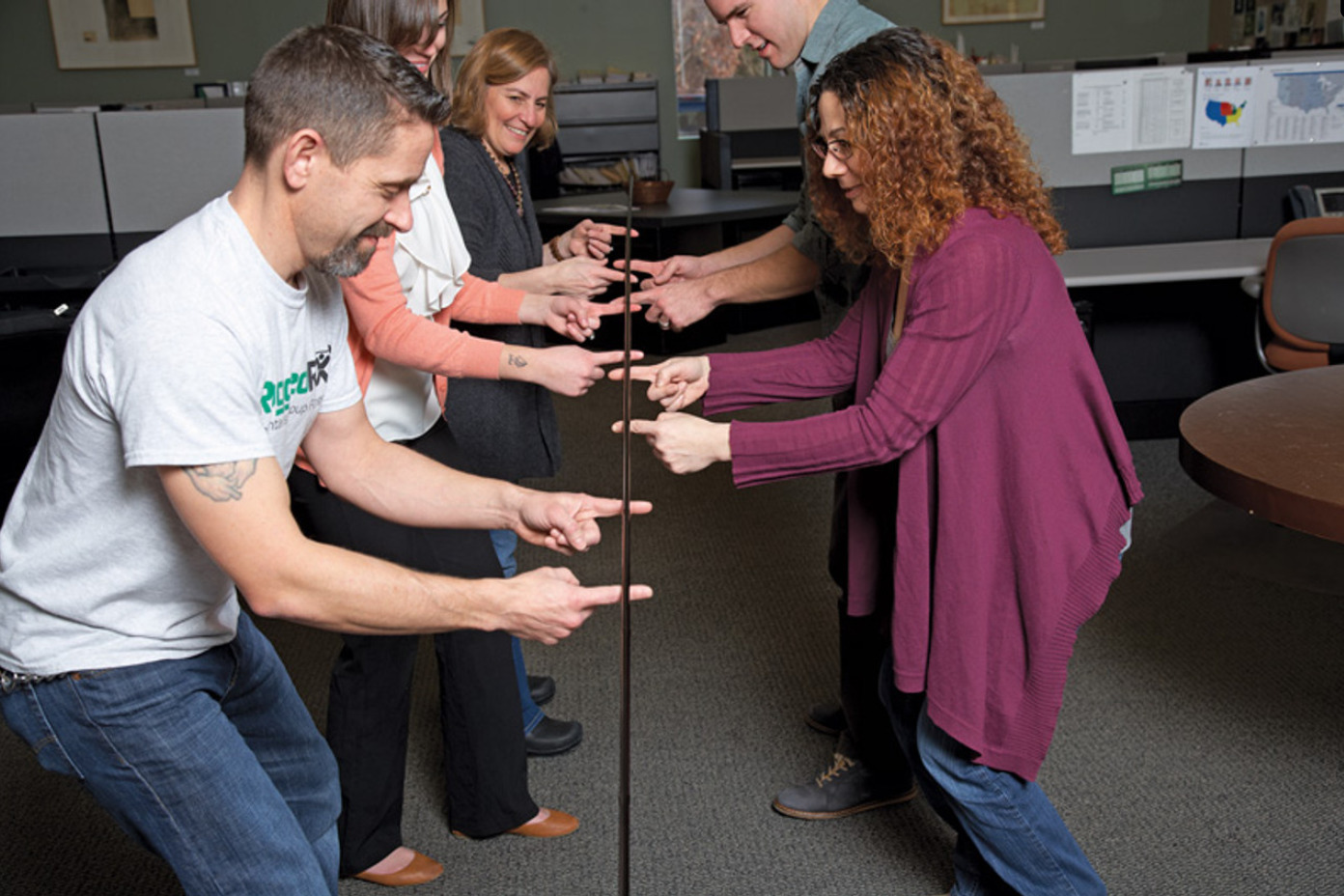 people lifting a stick with their index fingers
